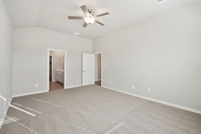 unfurnished bedroom featuring ceiling fan, light colored carpet, ensuite bathroom, and vaulted ceiling