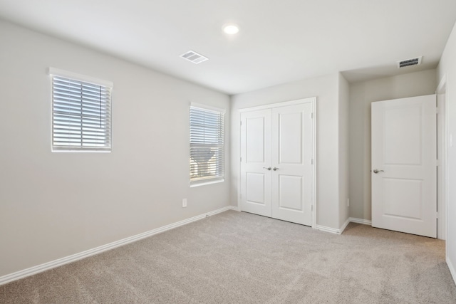 unfurnished bedroom with a closet and light carpet