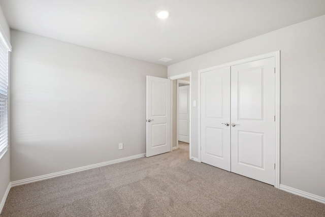 unfurnished bedroom featuring light colored carpet and a closet