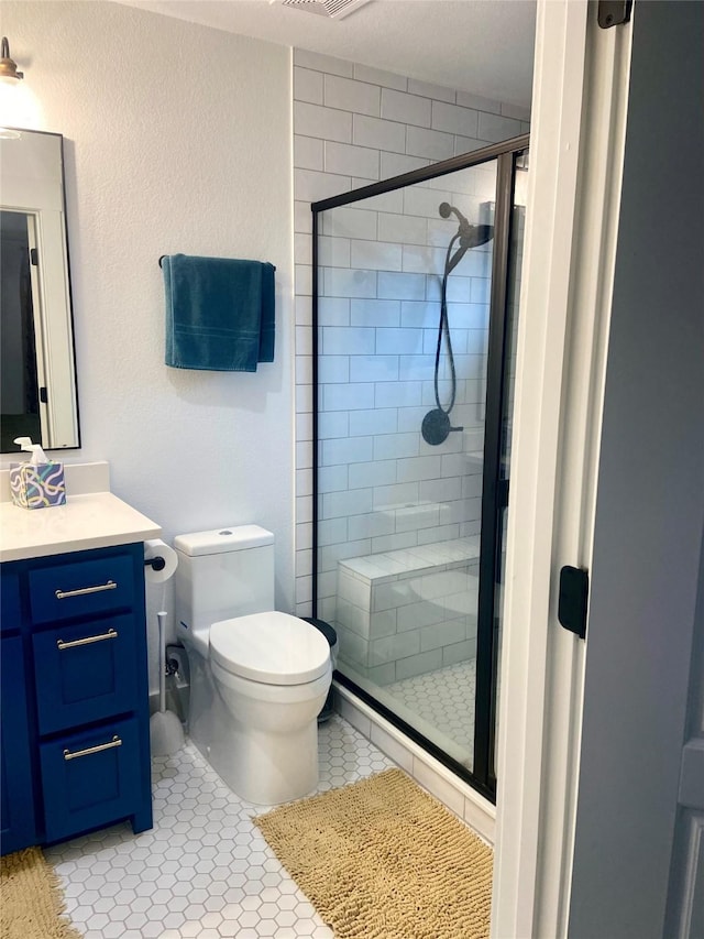 bathroom featuring vanity, tile patterned flooring, a shower with shower door, and toilet