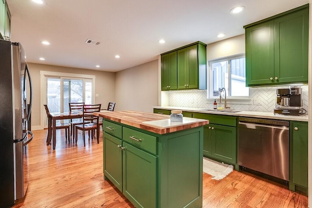 kitchen featuring sink, appliances with stainless steel finishes, a center island, light hardwood / wood-style floors, and green cabinetry