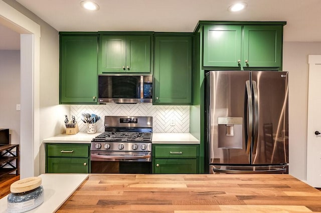 kitchen featuring green cabinets, decorative backsplash, and appliances with stainless steel finishes