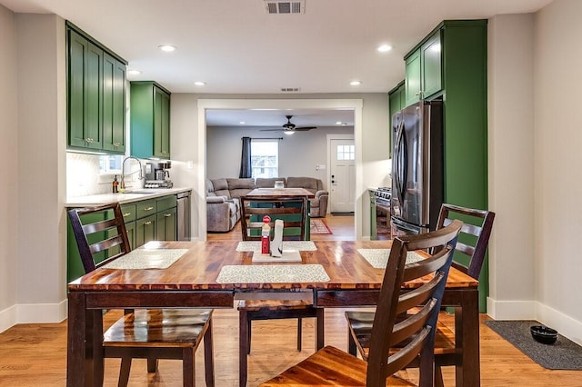 dining area with ceiling fan, sink, and light wood-type flooring