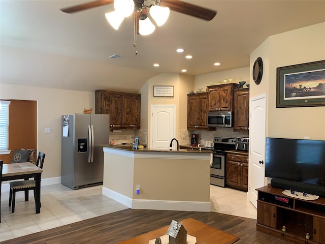 kitchen with stainless steel appliances, sink, an island with sink, and backsplash