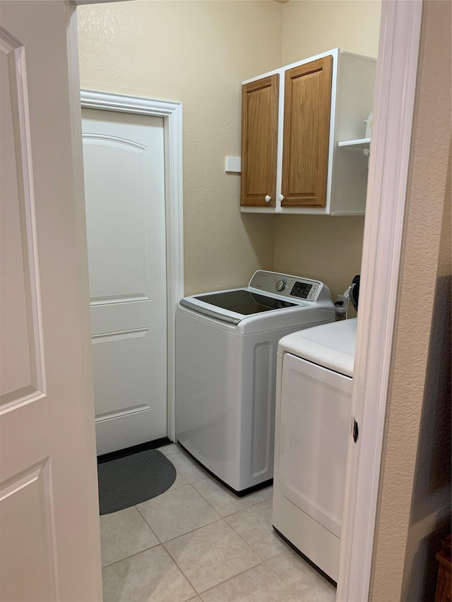 laundry room featuring light tile patterned flooring, cabinets, and washer and clothes dryer