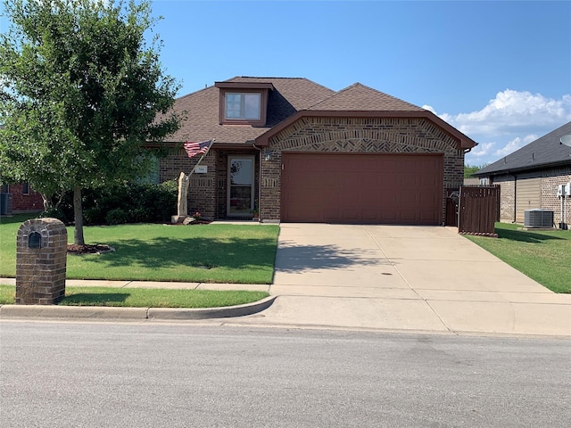 view of front of house with a garage, a front yard, and central AC unit