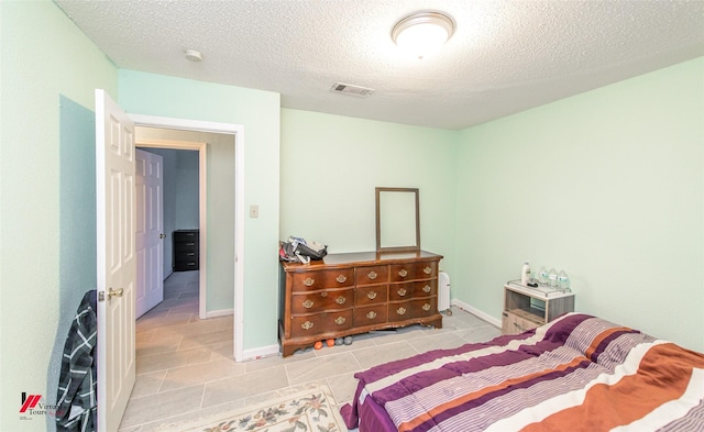 tiled bedroom with a textured ceiling