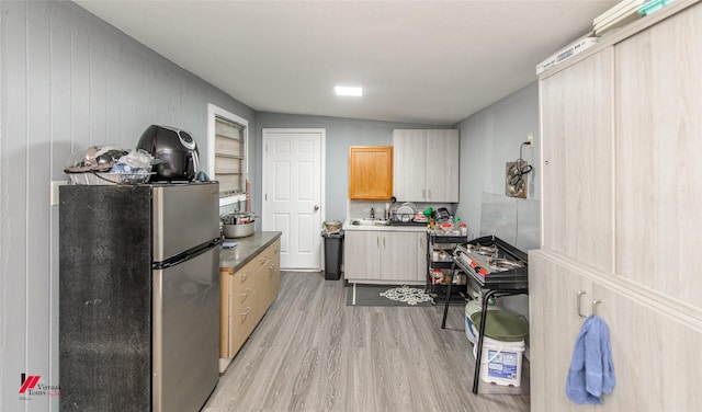 kitchen featuring light brown cabinetry, sink, stainless steel refrigerator, and light wood-type flooring