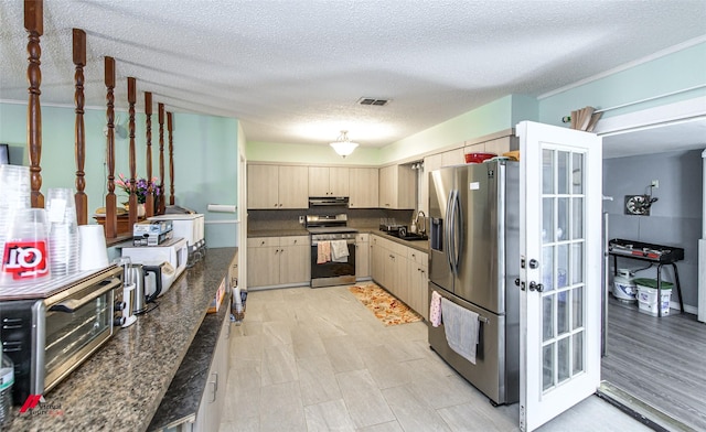 kitchen with appliances with stainless steel finishes, a textured ceiling, and light brown cabinets