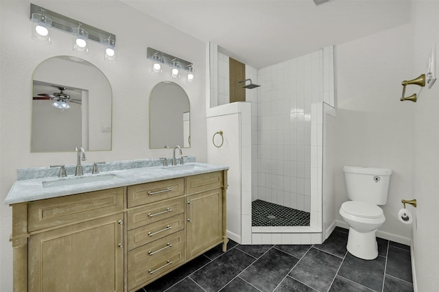 bathroom featuring tiled shower, toilet, vanity, ceiling fan, and tile patterned flooring