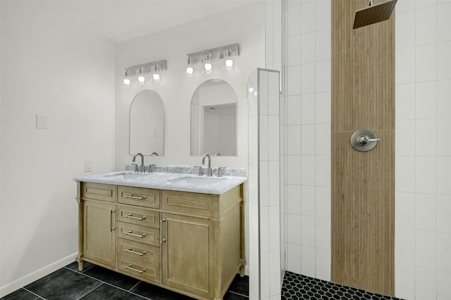 bathroom featuring tile patterned flooring, vanity, and a tile shower