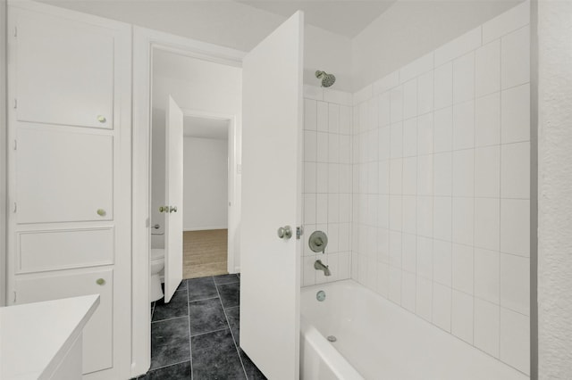 bathroom with toilet, tiled shower / bath combo, and tile patterned flooring