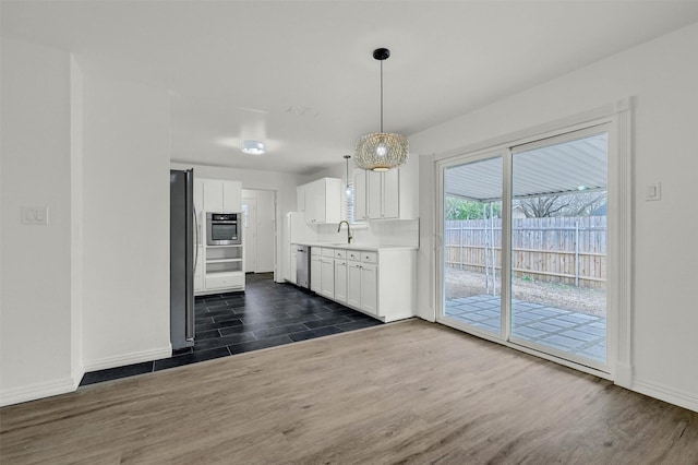 kitchen featuring sink, appliances with stainless steel finishes, white cabinetry, dark hardwood / wood-style floors, and decorative light fixtures