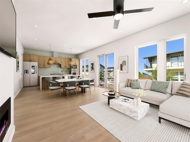 living room with ceiling fan, sink, and light hardwood / wood-style flooring