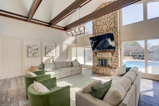 living room featuring hardwood / wood-style floors, high vaulted ceiling, a fireplace, beamed ceiling, and a notable chandelier