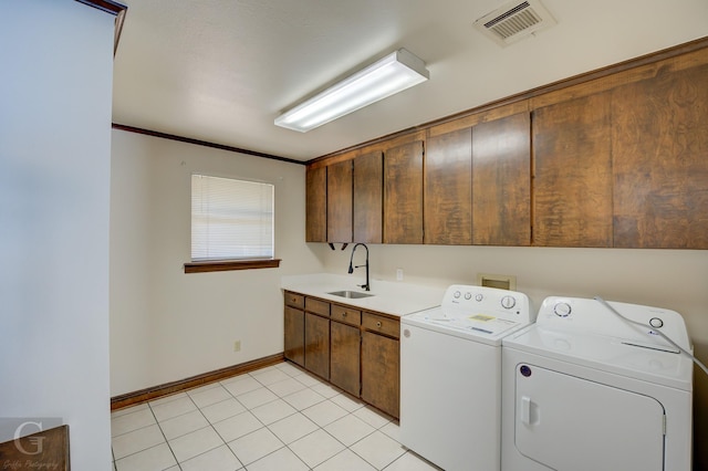 clothes washing area with sink, crown molding, light tile patterned floors, washing machine and dryer, and cabinets