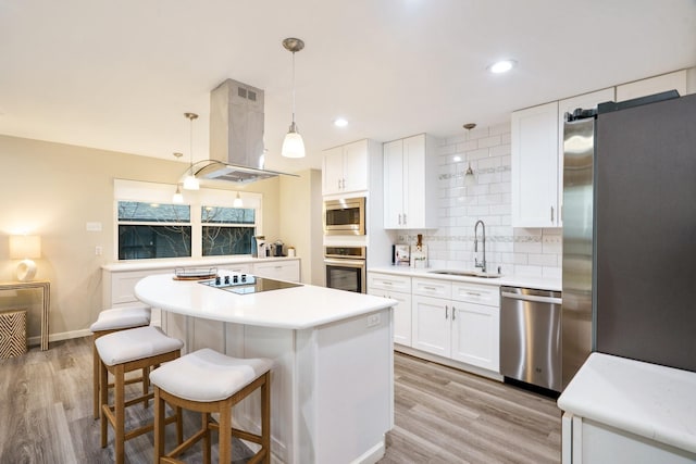 kitchen featuring sink, white cabinetry, island range hood, appliances with stainless steel finishes, and pendant lighting