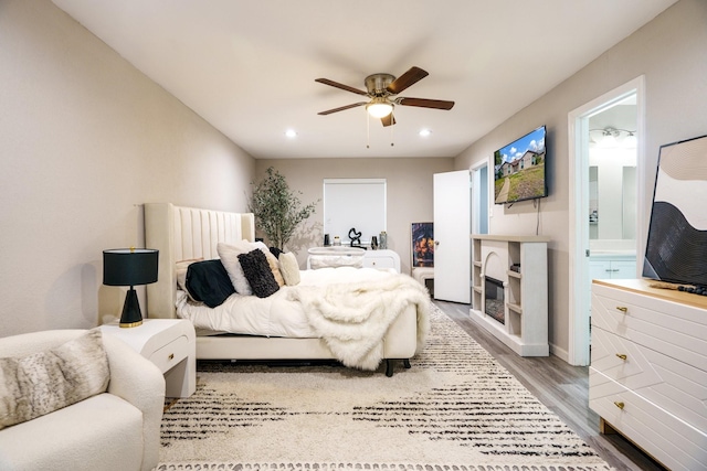 bedroom featuring hardwood / wood-style flooring, ensuite bath, and ceiling fan