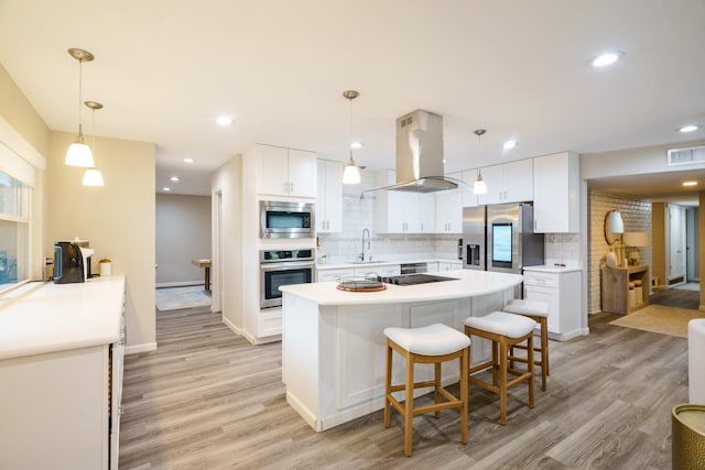 kitchen with pendant lighting, white cabinets, backsplash, island exhaust hood, and stainless steel appliances