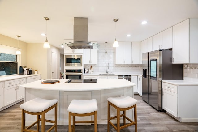 kitchen featuring sink, appliances with stainless steel finishes, white cabinetry, hanging light fixtures, and island range hood