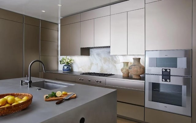 kitchen with tasteful backsplash, appliances with stainless steel finishes, sink, and white cabinets