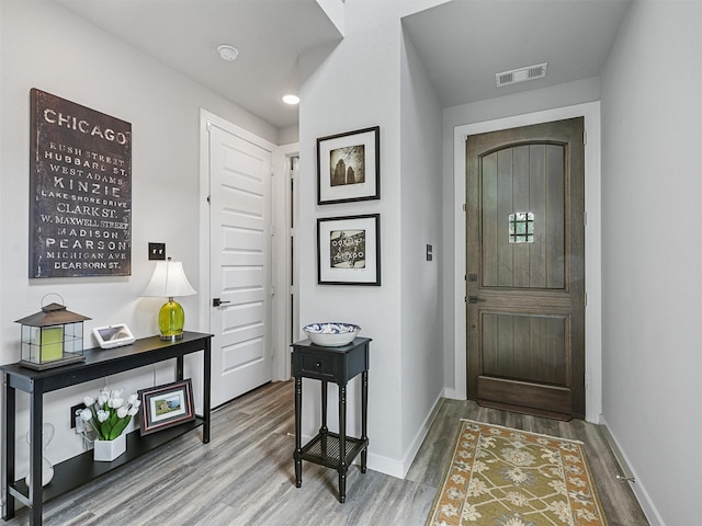 foyer entrance featuring wood finished floors, visible vents, and baseboards