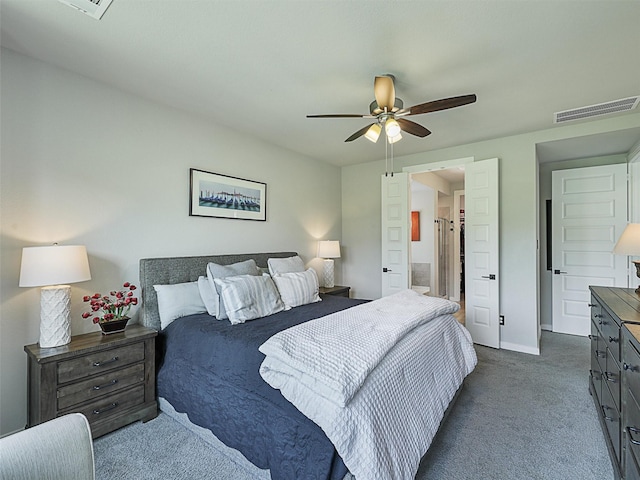 bedroom featuring visible vents, baseboards, dark carpet, ensuite bath, and a ceiling fan