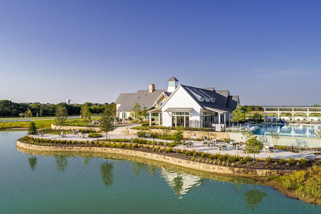 back of house with metal roof, a standing seam roof, and a water view