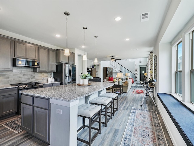 kitchen featuring visible vents, a kitchen bar, tasteful backsplash, a center island, and appliances with stainless steel finishes