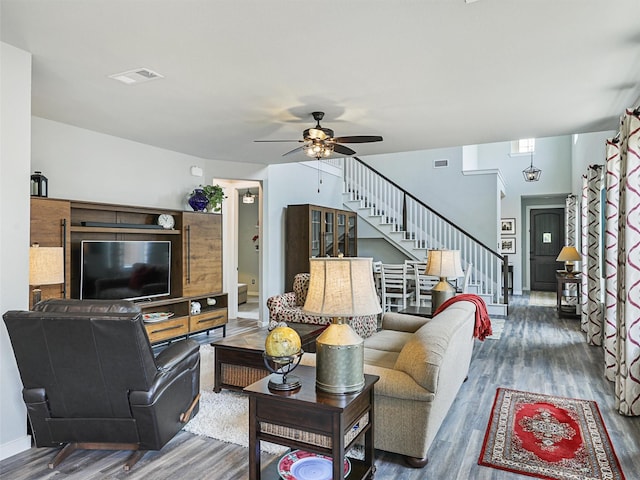 living room featuring stairway, visible vents, a ceiling fan, and wood finished floors