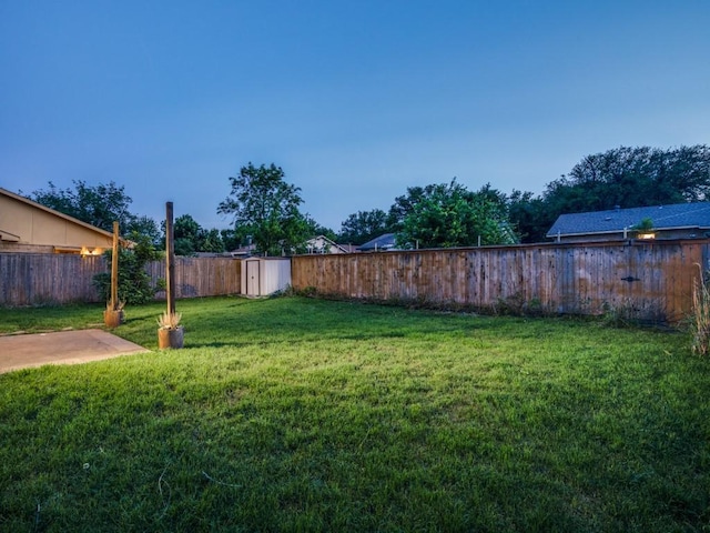 view of yard featuring a fenced backyard, a shed, and an outbuilding