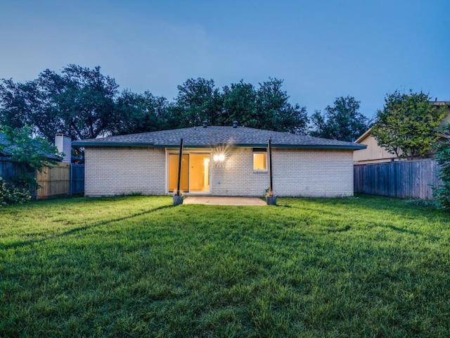back of property with a lawn, brick siding, and fence private yard