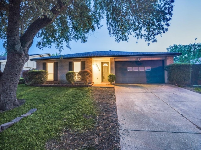 ranch-style house featuring concrete driveway, brick siding, an attached garage, and a front yard