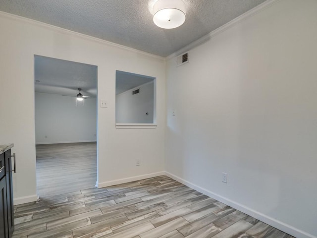 empty room with a ceiling fan, a textured ceiling, visible vents, crown molding, and light wood-type flooring