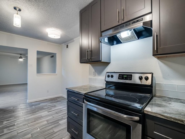 kitchen with visible vents, light wood-style floors, a textured ceiling, under cabinet range hood, and electric stove