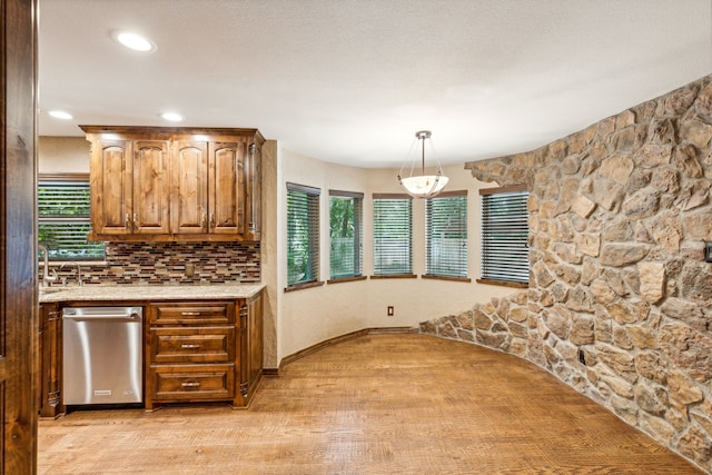 kitchen featuring tasteful backsplash, decorative light fixtures, a wealth of natural light, and light wood-type flooring