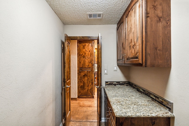 kitchen with light stone counters, wood-type flooring, and a textured ceiling