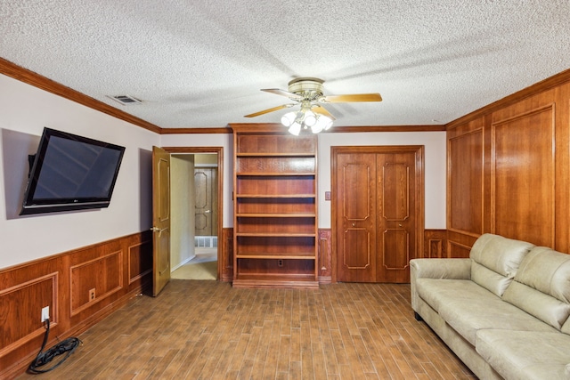 living room with hardwood / wood-style floors, crown molding, a textured ceiling, and ceiling fan