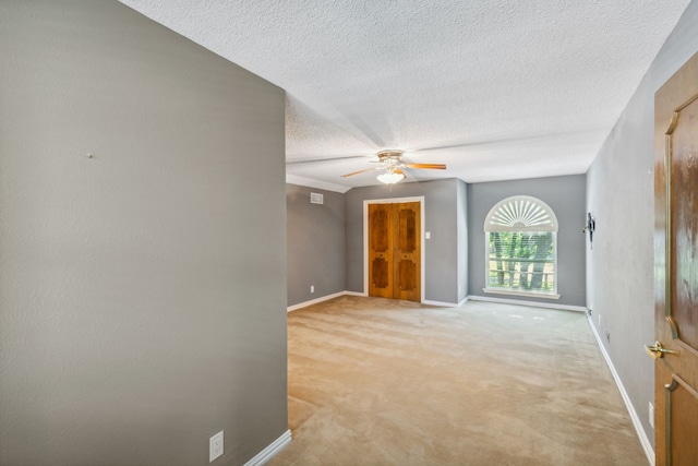 carpeted spare room with a textured ceiling and ceiling fan