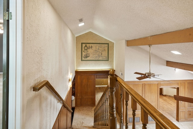 staircase featuring ceiling fan, vaulted ceiling, and a textured ceiling