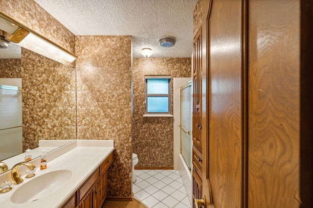 full bathroom with bath / shower combo with glass door, tile patterned flooring, vanity, toilet, and a textured ceiling