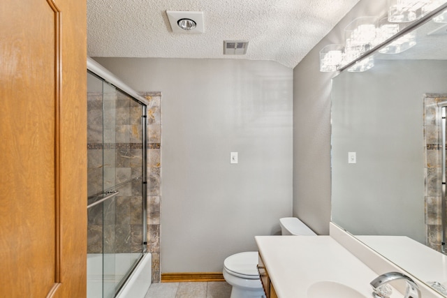 full bathroom with shower / bath combination with glass door, tile patterned flooring, vanity, a textured ceiling, and toilet