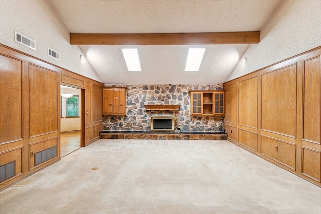 unfurnished living room featuring carpet floors, vaulted ceiling with beams, a fireplace, and a textured ceiling