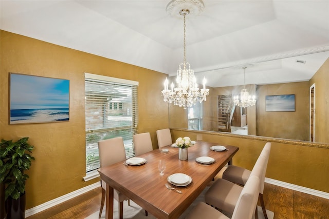 dining area featuring a chandelier, hardwood / wood-style floors, and a raised ceiling