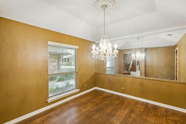 unfurnished dining area with a raised ceiling, hardwood / wood-style floors, and a notable chandelier