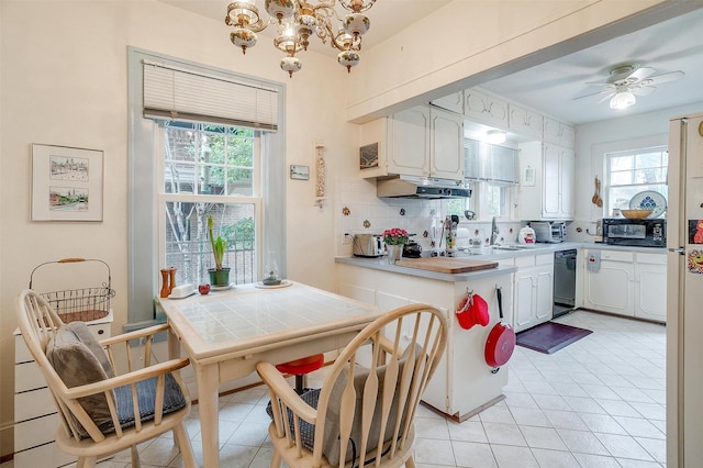 kitchen with light tile patterned floors, backsplash, white cabinetry, black appliances, and ceiling fan with notable chandelier