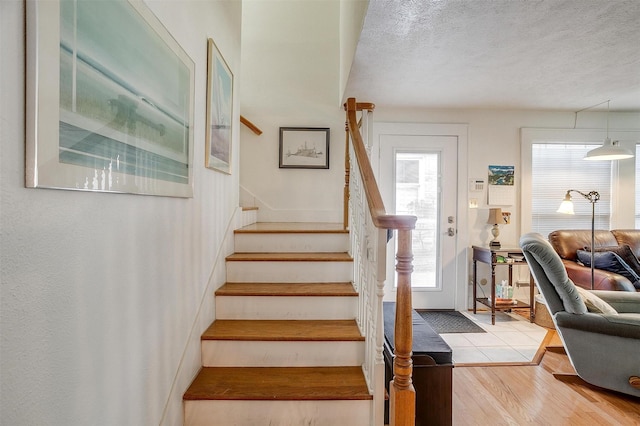 stairway with a textured ceiling and wood finished floors