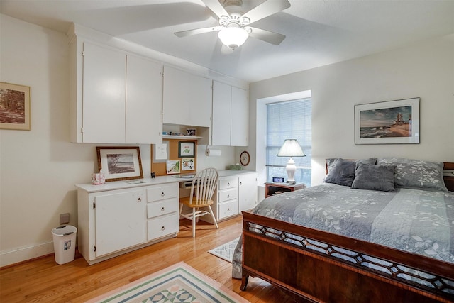 bedroom with light wood-style flooring, baseboards, ceiling fan, and built in study area