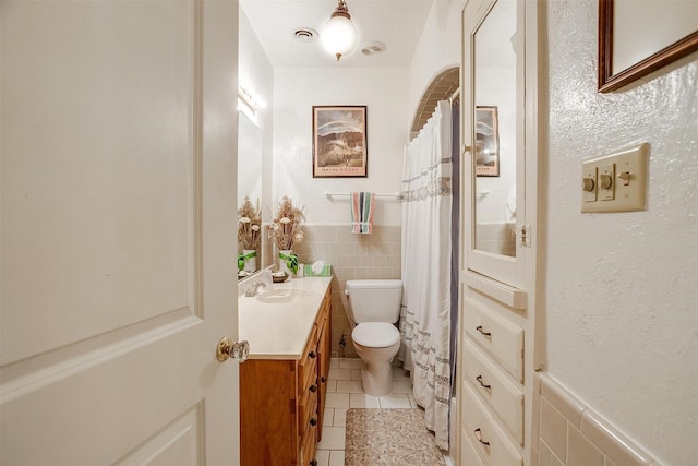 full bath with visible vents, wainscoting, toilet, tile patterned floors, and tile walls