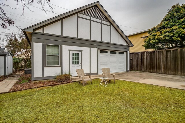 exterior space featuring concrete driveway, fence, a yard, an outdoor structure, and stucco siding